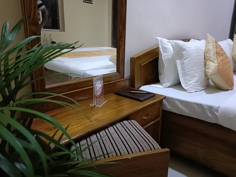 Fresh towels folded on a luggage bench beside a made bed — Shree Chaitanya Gaudiya Math, Puri