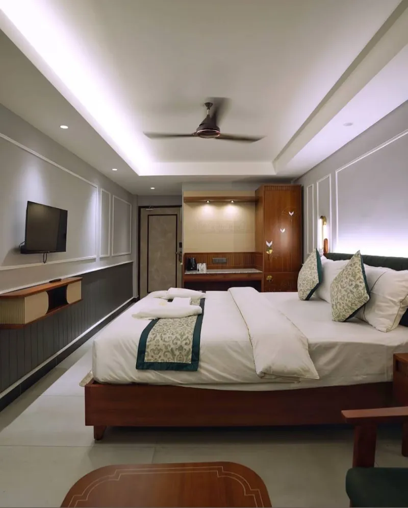 A long deluxe room with a recessed ceiling and a television — Shree Chaitanya Gaudiya Math, Puri