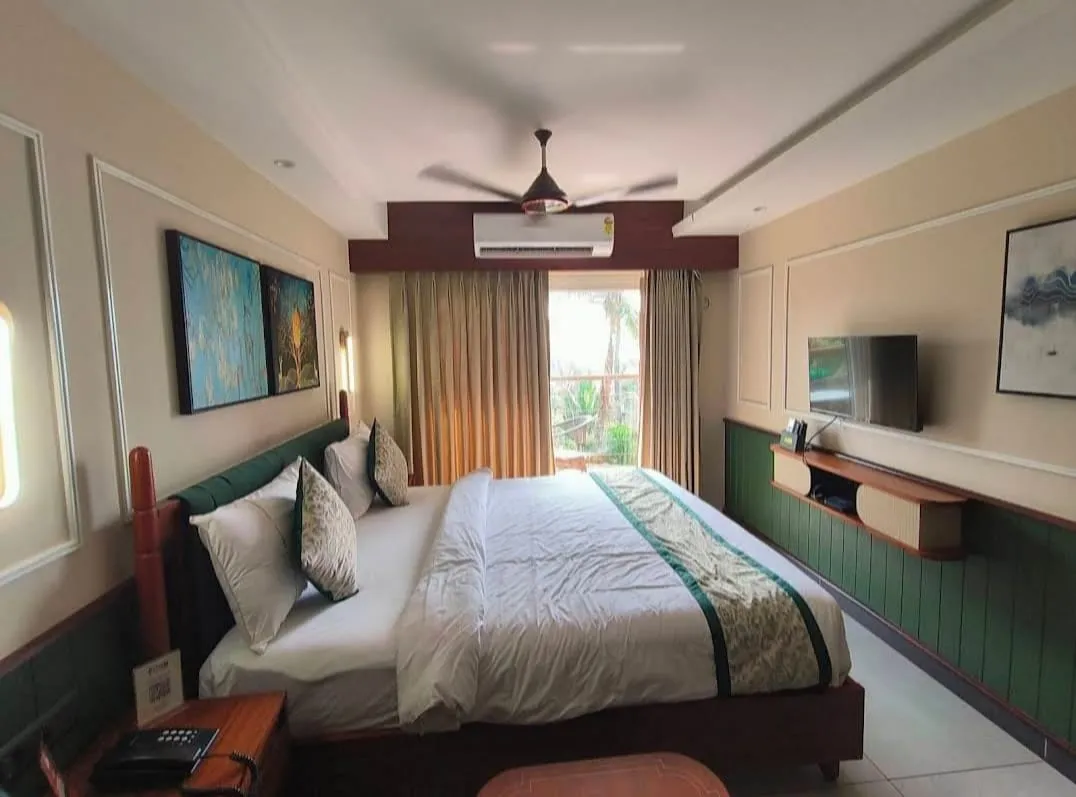 An air-conditioned double room with a panelled headboard wall, long desk and television — Shree Chaitanya Gaudiya Math, Puri
