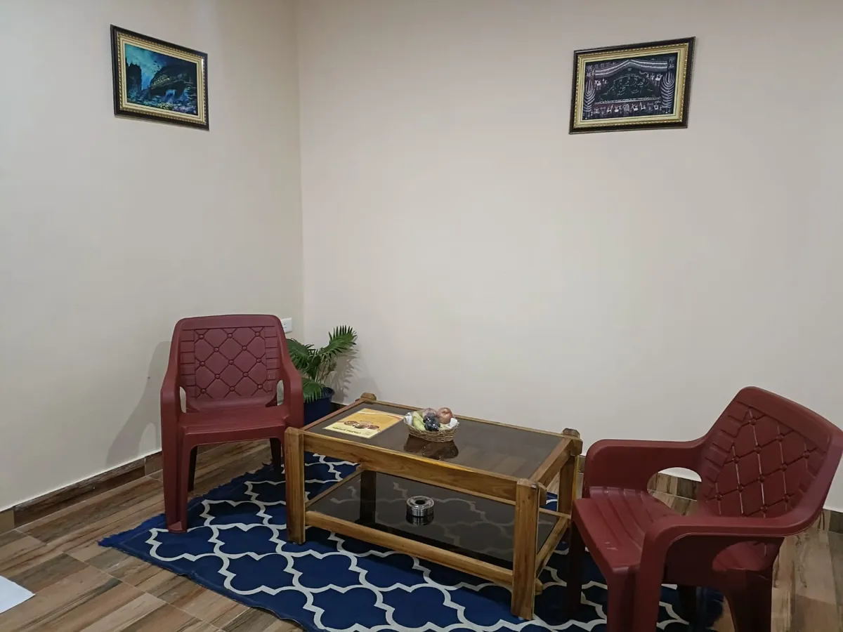 A seating corner with two chairs, a low table and a rug — Shree Chaitanya Gaudiya Math, Puri