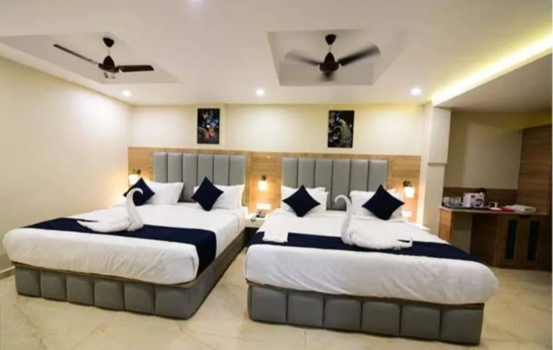 A large room with two twin beds against upholstered headboards and a writing desk — Shree Chaitanya Gaudiya Math, Puri